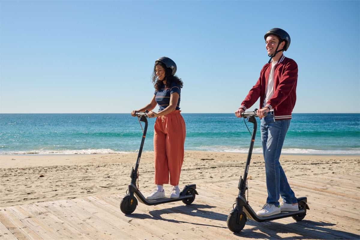 Due persone con il casco in monopattino elettrico su una passerella al mare: può sostituire l'auto per andare al lavoro?