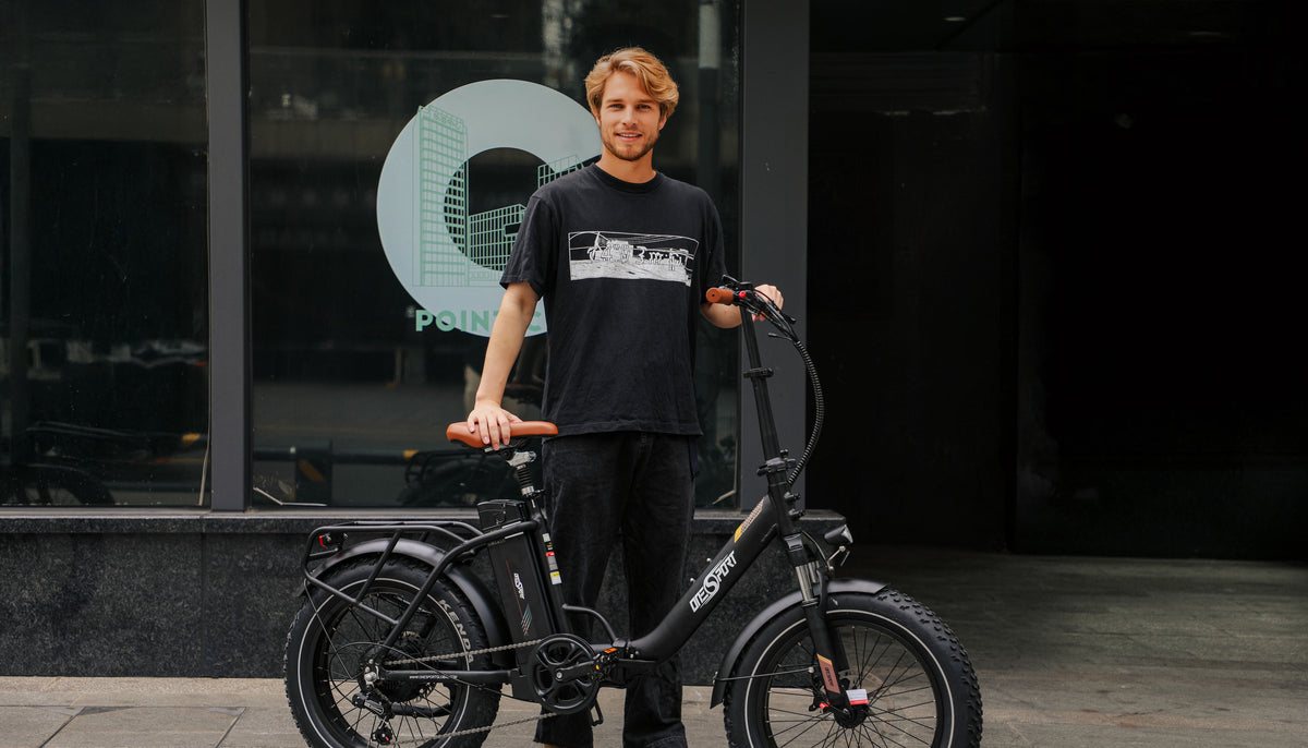 Uomo in piedi con la fat bike elettrica pieghevole OneSport OT16 Max in colore nero su sfondo scuro