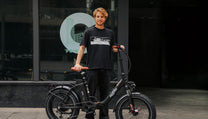 Uomo in piedi con la fat bike elettrica pieghevole OneSport OT16 Max in colore nero su sfondo scuro