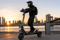 Uomo in piedi con il monopattino elettrico DUALTRON VICTOR LIMITED in città al tramonto