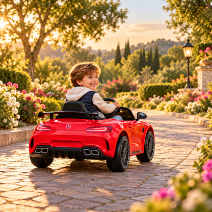 Bambino alla guida dell'auto elettrica per bambini Mercedes AMG GT in colore rosso in un parco