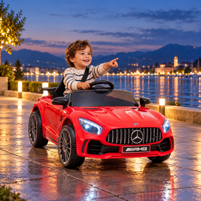 Bambino alla guida dell'auto elettrica per bambini Mercedes AMG GT in riva al mare