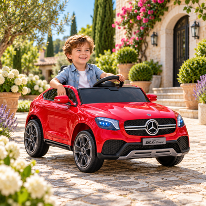 Bambino alla guida dell'auto elettrica per bambini Mercedes GLC Coupé in un parco