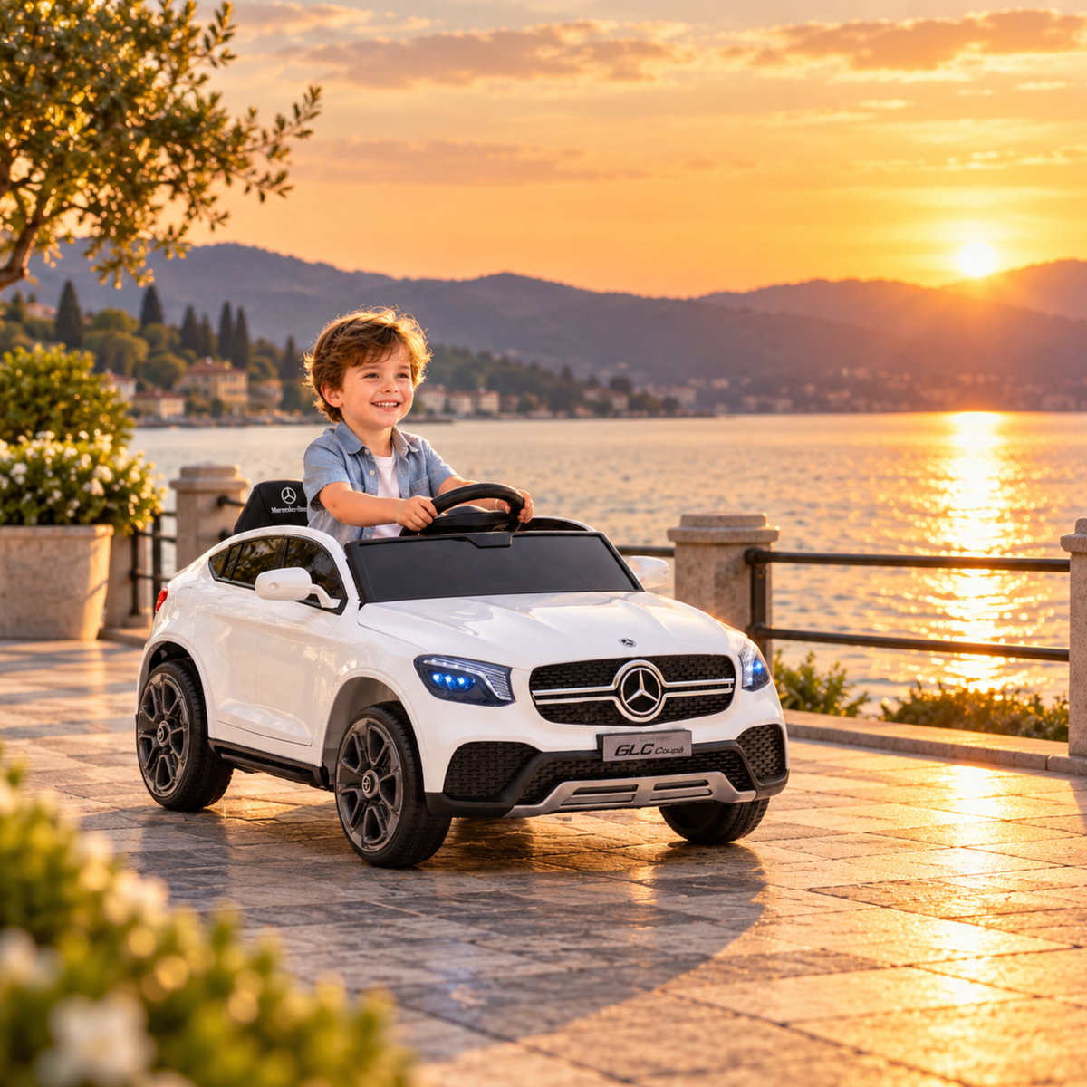 Bambino alla guida dell'auto elettrica per bambini Mercedes GLC Coupé in riva al mare