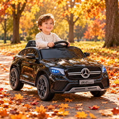 Bambino alla guida dell'auto elettrica per bambini Mercedes GLC Coupé in colore nero in un parco