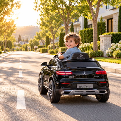 Bambino alla guida dell'auto elettrica per bambini Mercedes GLC Coupé su un vialetto