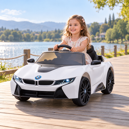 Bambino alla guida dell'auto elettrica per bambini BMW i8 Coupé in riva al mare, da un'altra angolazione