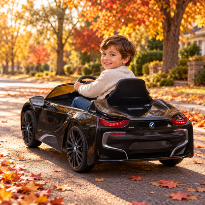 Bambino alla guida dell'auto elettrica per bambini BMW i8 Coupé in un parco, in primo piano