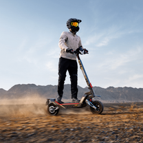 Persona in piedi con il monopattino elettrico NAVEE XT5 Max su terreno sabbioso