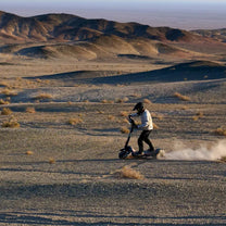 Pilota con il monopattino elettrico NAVEE XT5 Max in fuoristrada su terreno sabbioso