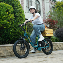 Donna alla guida della fat bike elettrica URLIFE E20 in colore verde con cestino posteriore su un vialetto