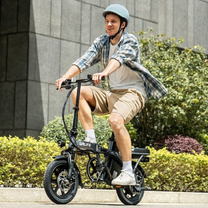 Uomo alla guida della bici elettrica pieghevole URLIFE F1L in colore nero con il casco in città