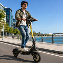 Uomo con casco in sella a un monopattino elettrico Wheely - H7 lungo una banchina sull'acqua