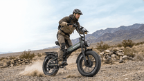 Persona alla guida della fat bike elettrica pieghevole APEFOX RH20 su un prato