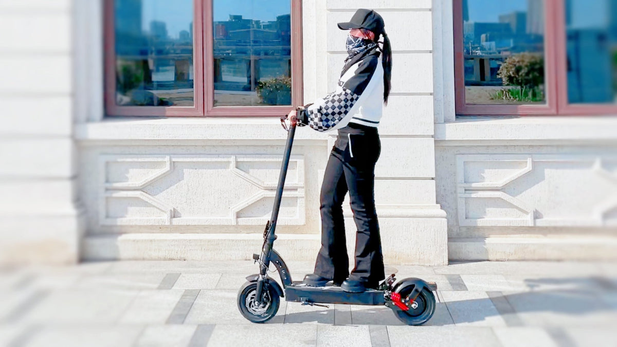 Donna in piedi con il monopattino elettrico DriveTron DT08 in città