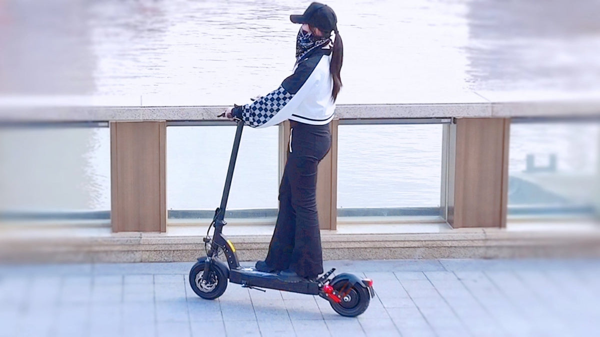 Donna alla guida del monopattino elettrico DriveTron DT08 in città