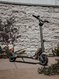 Monopattino elettrico DUALTRON TOGO visto di tre quarti in un giardino
