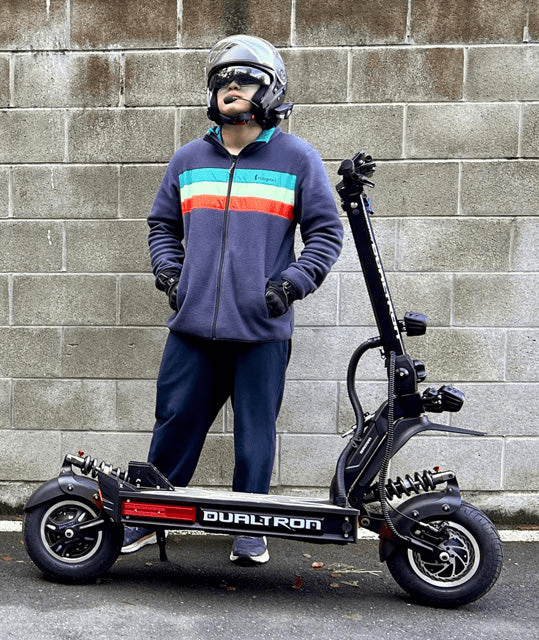 Uomo in piedi con il monopattino elettrico DUALTRON X LIMITED con il casco