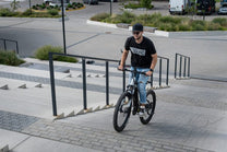 Uomo alla guida della mountain bike elettrica Duotts E29 su un vialetto
