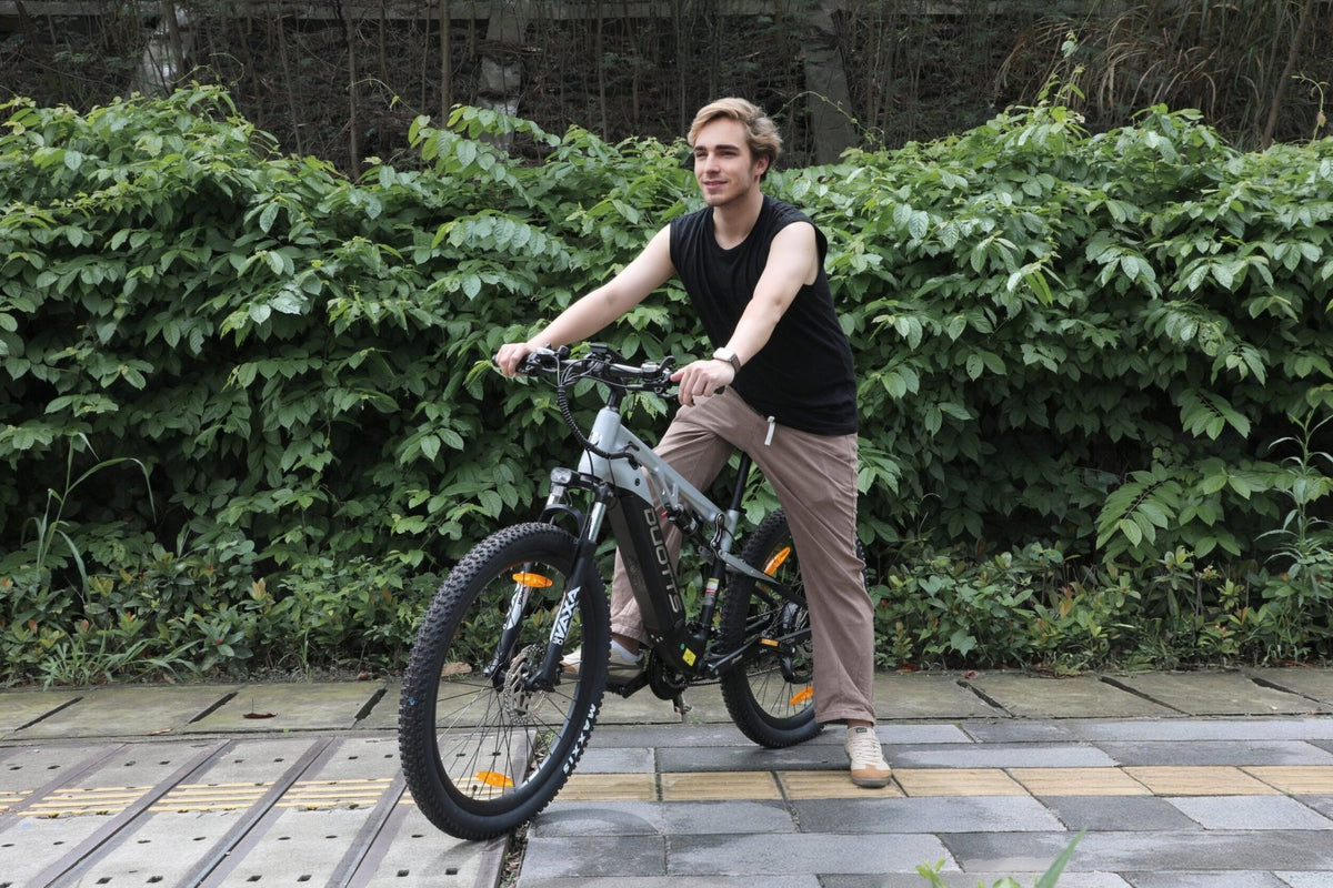 Donna in piedi con la mountain bike elettrica Duotts E29 in un parco