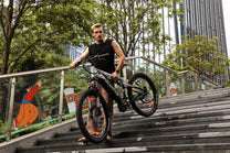 Donna in piedi con la mountain bike elettrica Duotts E29 in un parco