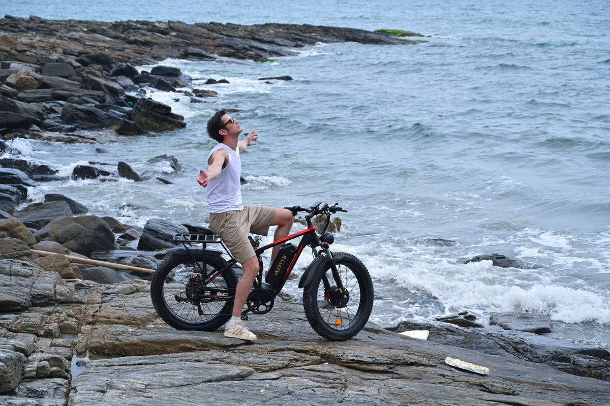 Uomo in piedi con la fat bike elettrica Duotts S26 in riva al mare