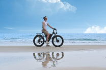 Uomo in piedi con la fat bike elettrica Duotts S26 in riva al mare