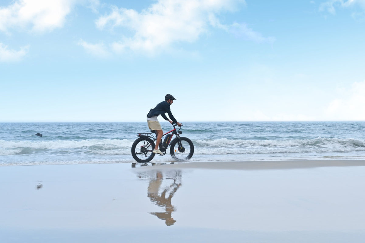 Uomo alla guida della fat bike elettrica Duotts S26 in riva al mare