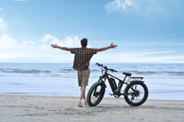 Uomo in piedi con la fat bike elettrica Duotts S26 in riva al mare