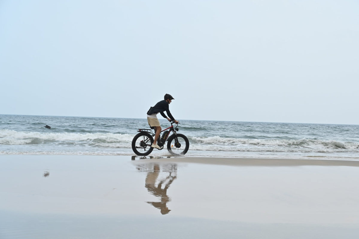 Uomo alla guida della fat bike elettrica Duotts S26 in riva al mare