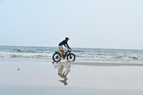 Uomo alla guida della fat bike elettrica Duotts S26 in riva al mare