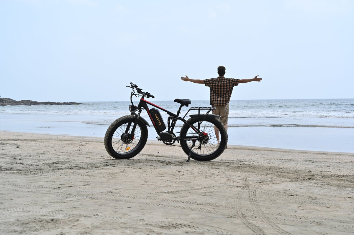Uomo in piedi con la fat bike elettrica Duotts S26 in riva al mare