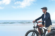 Uomo in piedi con la fat bike elettrica Duotts S26 in riva al mare