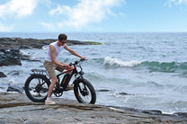 Uomo in piedi con la fat bike elettrica Duotts S26 in riva al mare