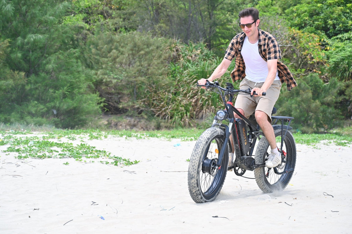 Uomo alla guida della fat bike elettrica Duotts S26 in riva al mare