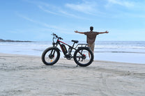 Uomo in piedi con la fat bike elettrica Duotts S26 in riva al mare
