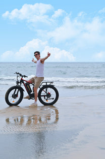 Uomo in piedi con la fat bike elettrica Duotts S26 in riva al mare
