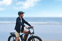 Uomo in piedi con la fat bike elettrica Duotts S26 in riva al mare