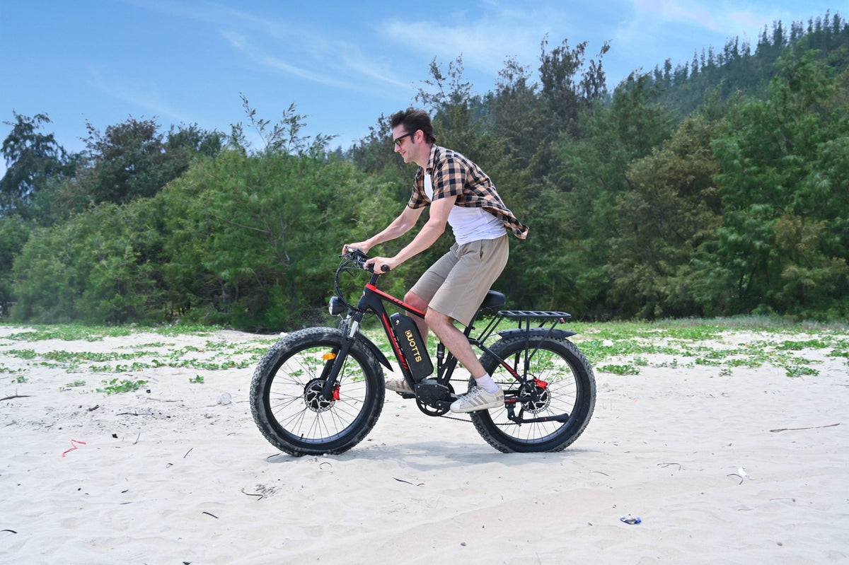 Uomo alla guida della fat bike elettrica Duotts S26 in riva al mare