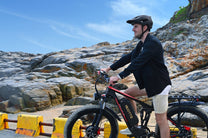 Uomo in piedi con la fat bike elettrica Duotts S26 in riva al mare