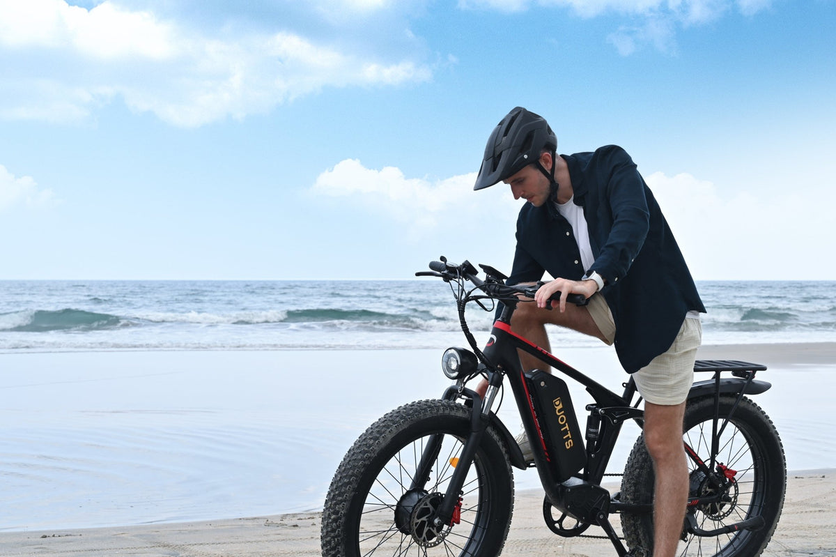 Uomo in piedi con la fat bike elettrica Duotts S26 in riva al mare