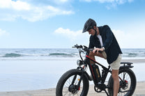 Uomo in piedi con la fat bike elettrica Duotts S26 in riva al mare