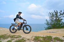 Uomo alla guida della fat bike elettrica Duotts S26 in riva al mare