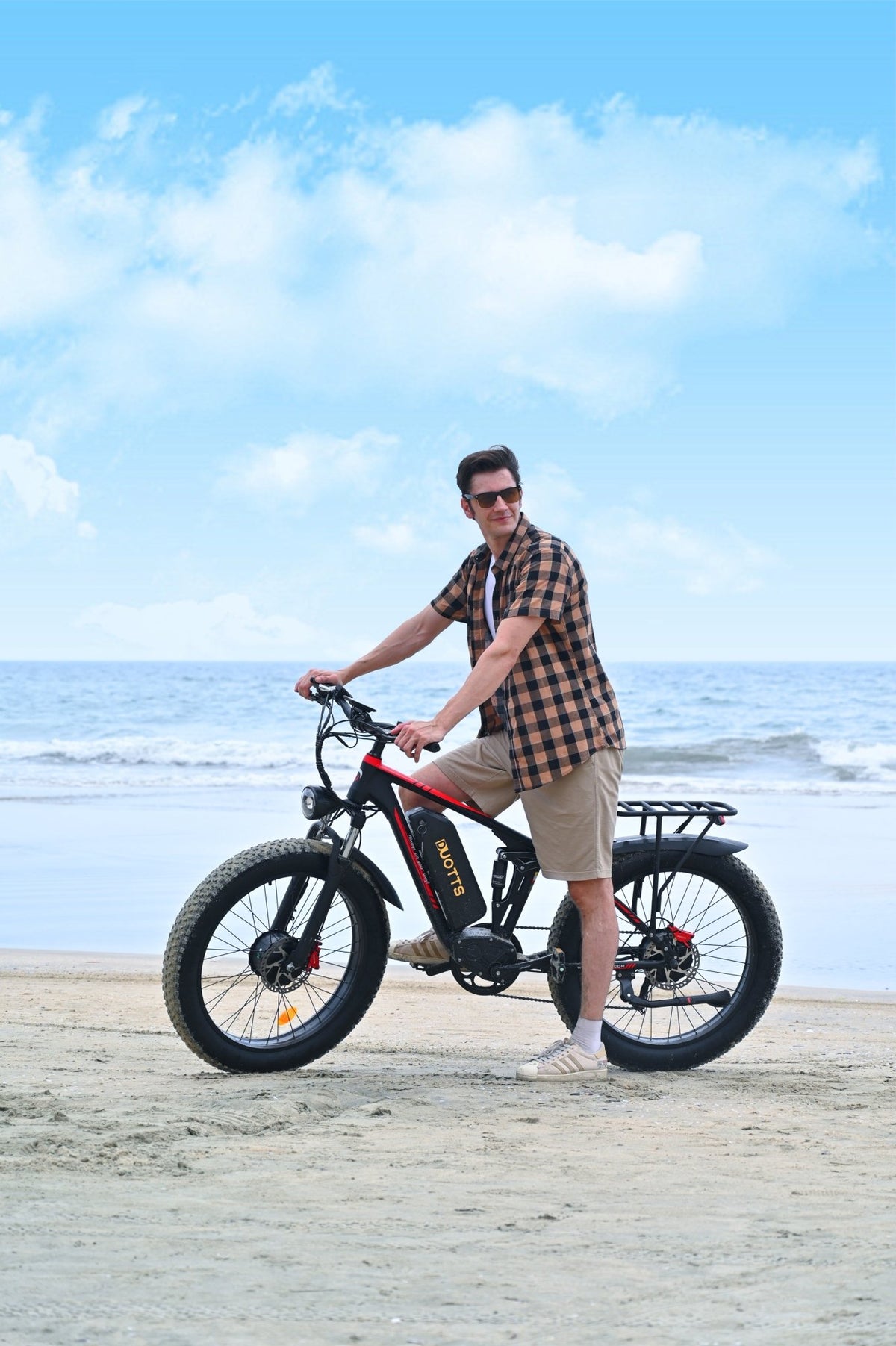 Uomo in piedi con la fat bike elettrica Duotts S26 in riva al mare