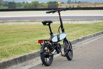 Bici elettrica pieghevole DYU C2, vista di tre quarti da dietro su un sentiero pedonale