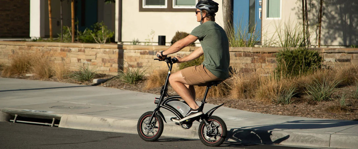 Uomo alla guida della bici elettrica pieghevole DYU D3S su un vialetto