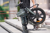 Persona che porta la bici elettrica pieghevole DYU T1 piegata