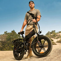 Uomo in piedi con la fat bike elettrica pieghevole ENGWE ENGINE X su terreno sabbioso