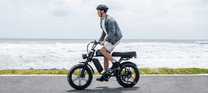 Uomo alla guida della fat bike elettrica ENGWE M1 in riva al mare