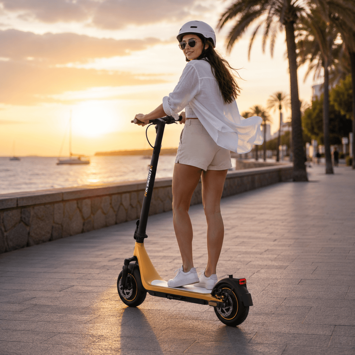Donna in piedi con il monopattino elettrico HIKERBOY CURTIS DUAL PRO al tramonto